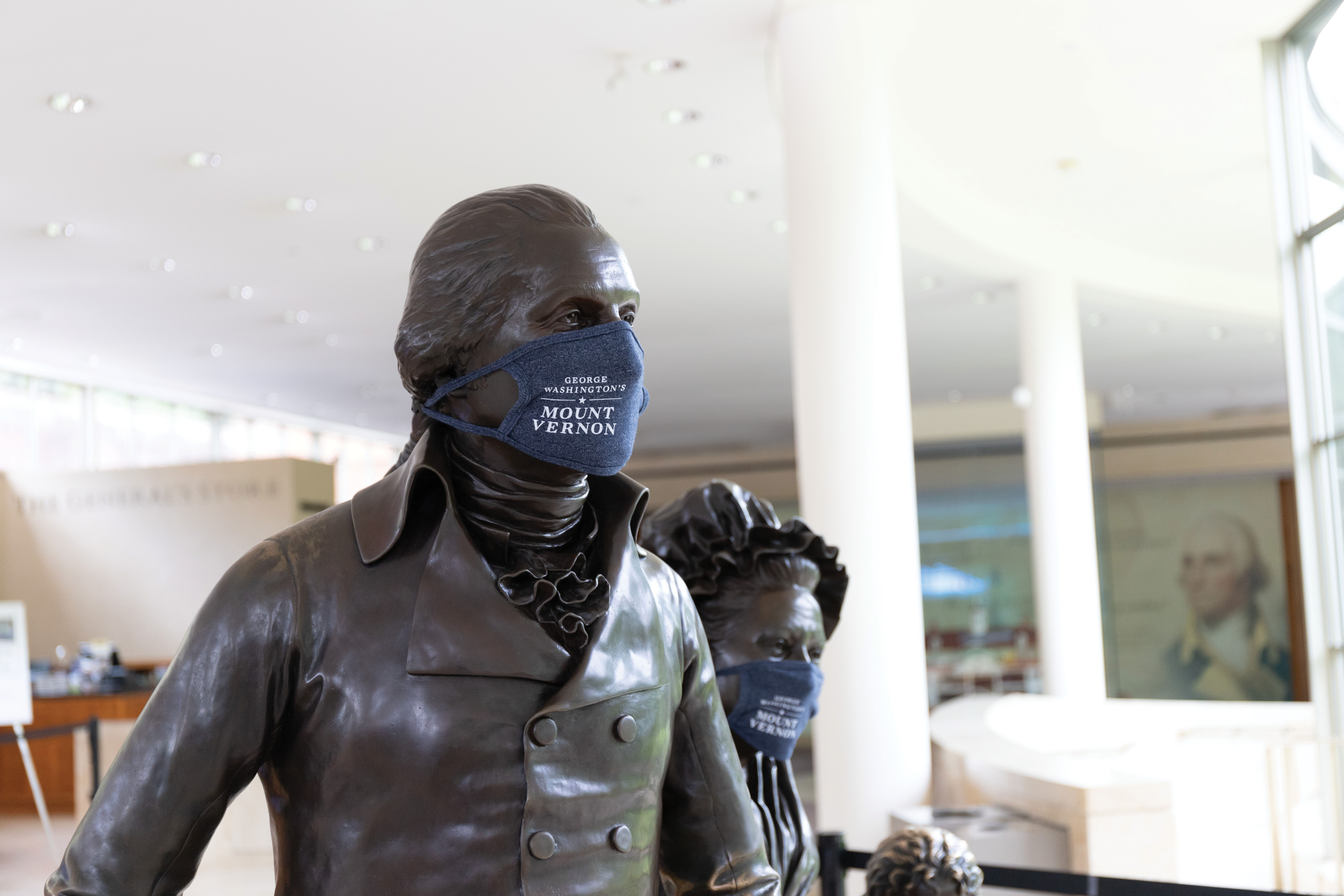 Image of statues of George and Matha Washington wearing masks