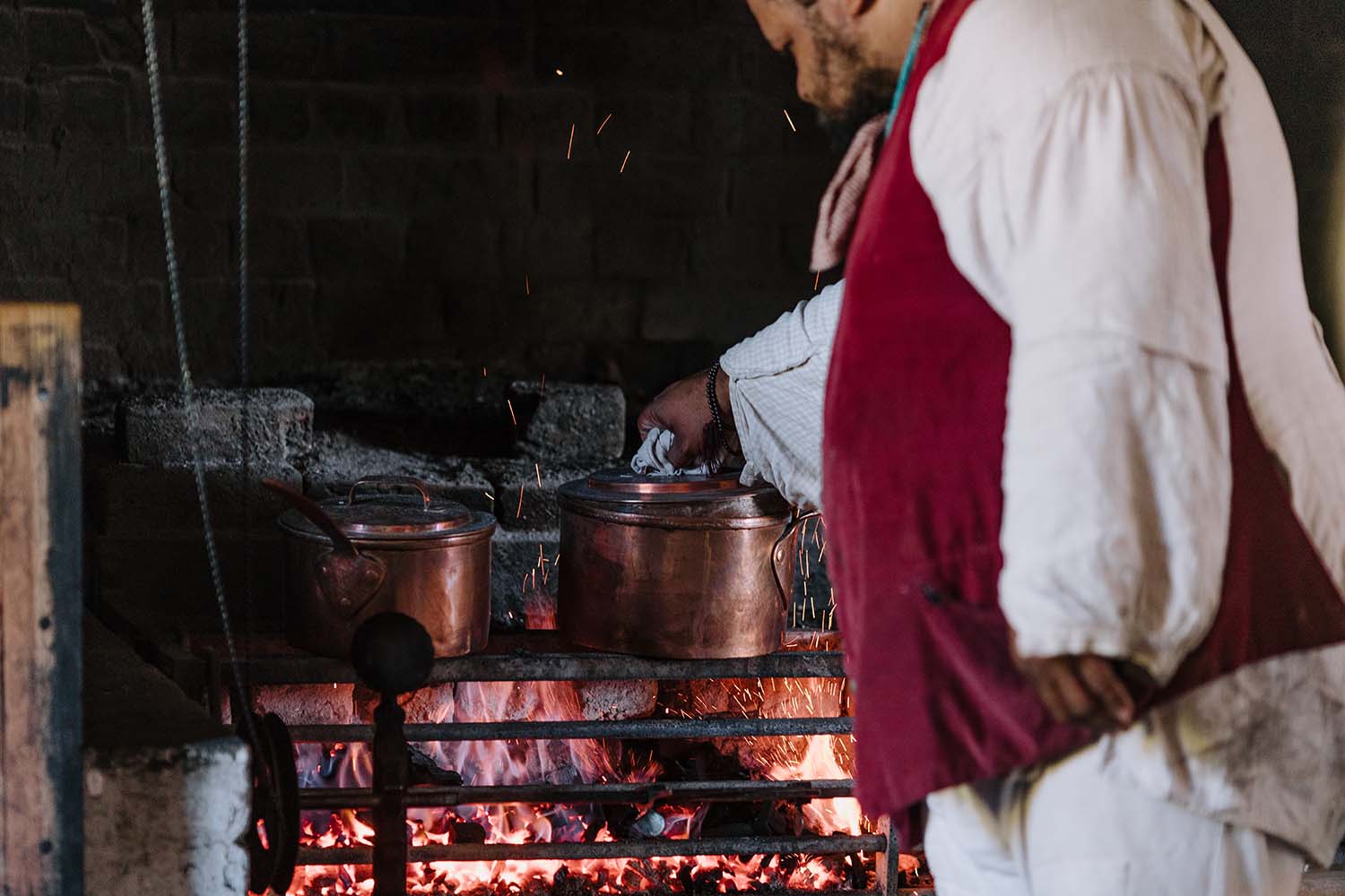 Michael Twitty checks on food cooking over the fire