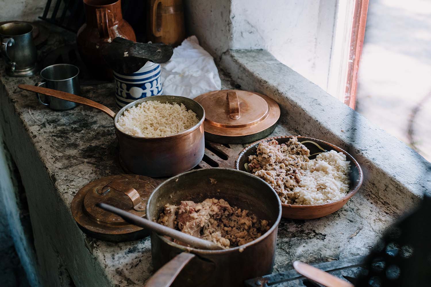 Cooked black-eyed pea and rice sit in copper pots on the window sill