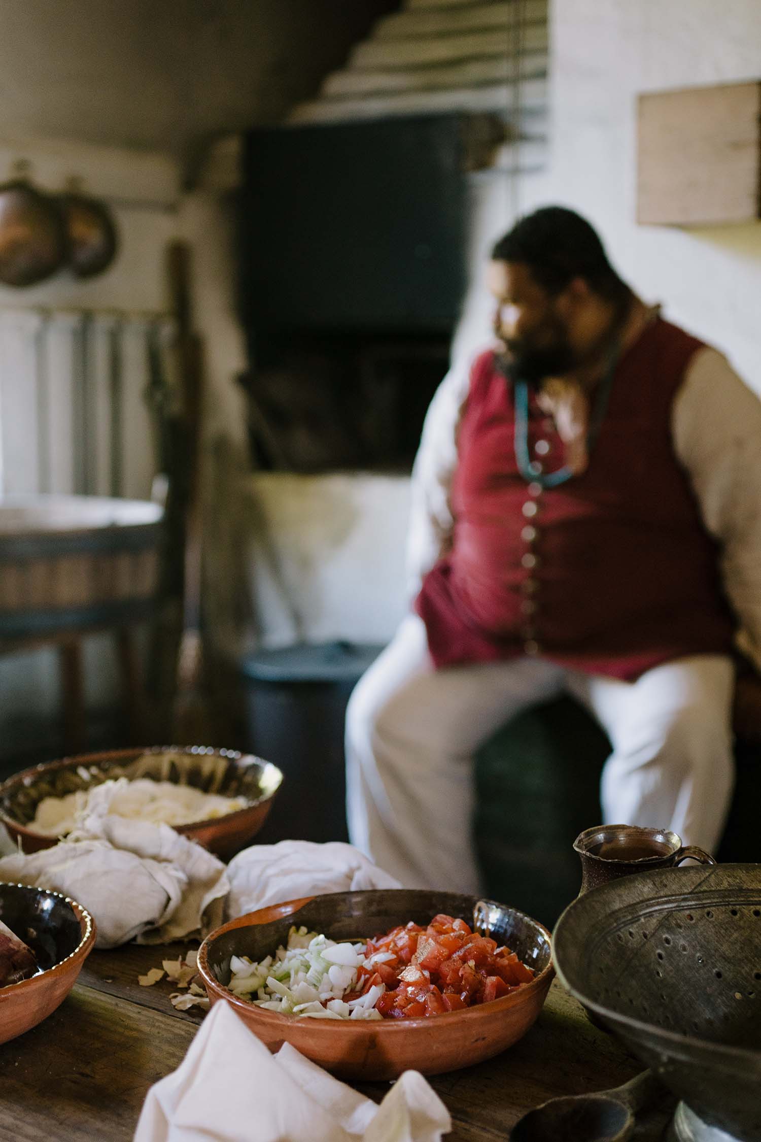 Prepared food sits on the table in the foreground. Michael Twitty sits in the background.